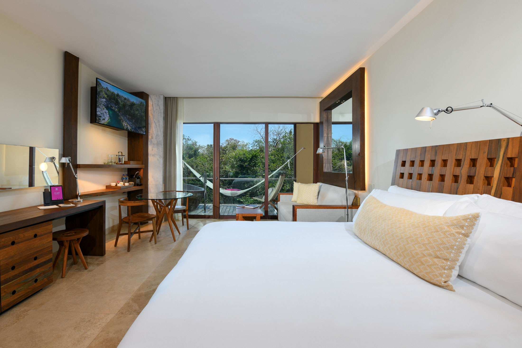 A king bedroom opening onto a leafy balcony at Hotel Xcaret Mexico